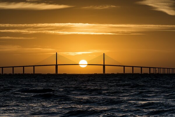 Naranja puesta de sol en el mar sobre el puente