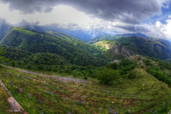 A meadow with hills over which clouds float