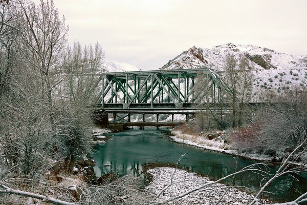 Winter Bild der Brücke auf dem Hintergrund von Bergen und Bäumen