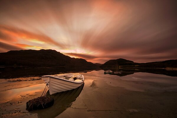 Boat on the shore of the lake with sunset