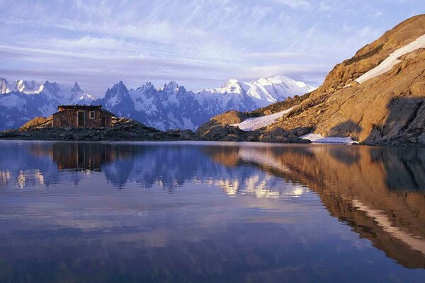 Himmel, Hütte und Berge in der Reflexion des Sees