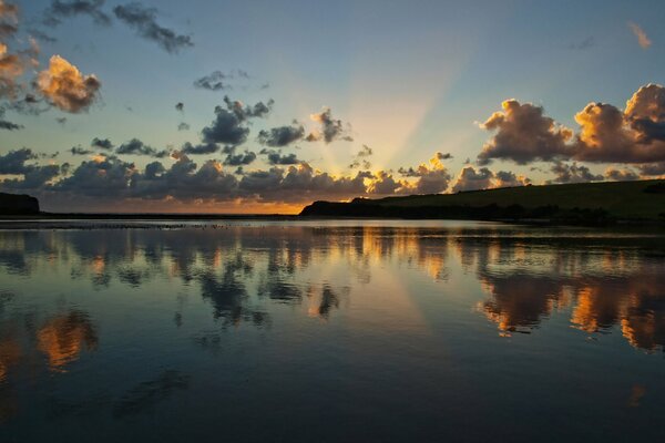 Amanecer en el río con el reflejo de las nubes en el agua