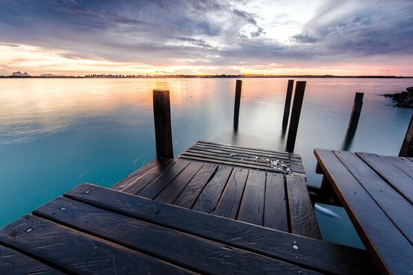 Molo di legno sul fiume al tramonto