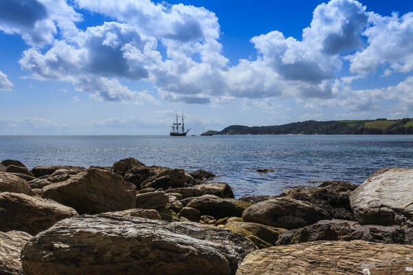 Voilier en mer. Vue depuis le rivage rocheux