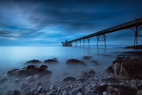 Pier in the distance against the background of a foggy sea and blue sky