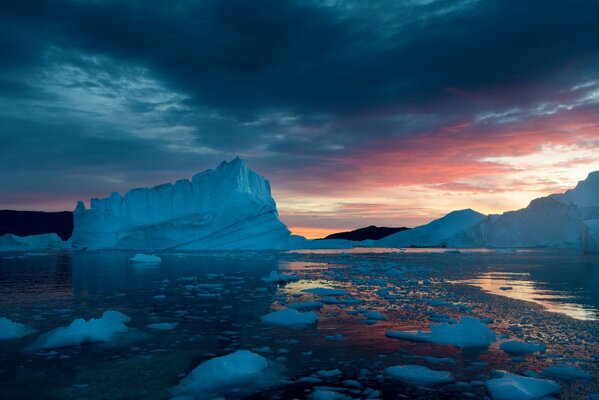 Montañas cubiertas de nieve témpanos de hielo puesta de sol nubes de plomo