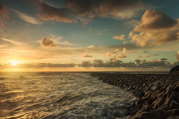 Sea foam rocky shore clouds sun at sunset