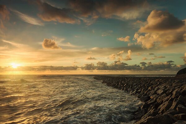 Морская пена каменистый берег тучи солнце в закате