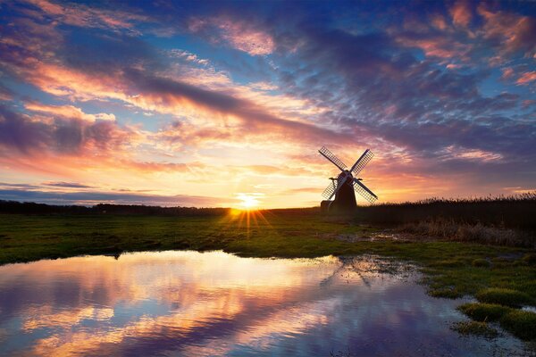 Le moulin se dresse sur le bouleau du lac. Beau coucher de soleil se reflète dans l eau