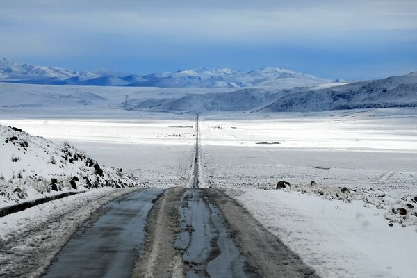 A long road in winter through the fields