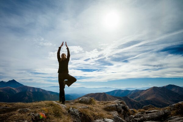 A girl does yoga in the mountains