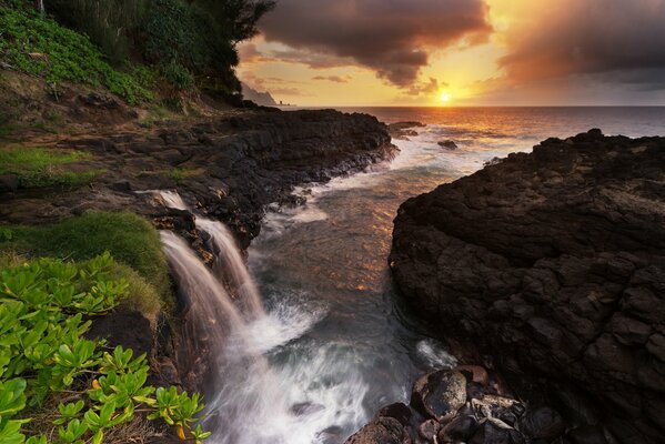 Cascade sur fond de mer et de rochers au coucher du soleil