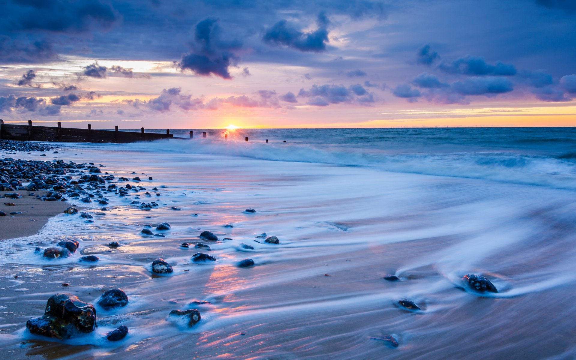 großbritannien england norfolk meer küste steine brandung abend sonnenuntergang sonne horizont himmel wolken wolken