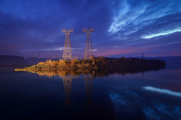 Líneas de transmisión en el reflejo del agua, en el fondo del cielo nocturno azul oscuro