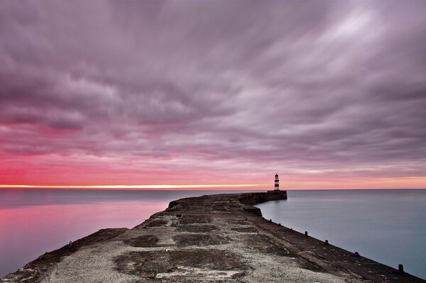 Aube sur la mer. Jetée et phare