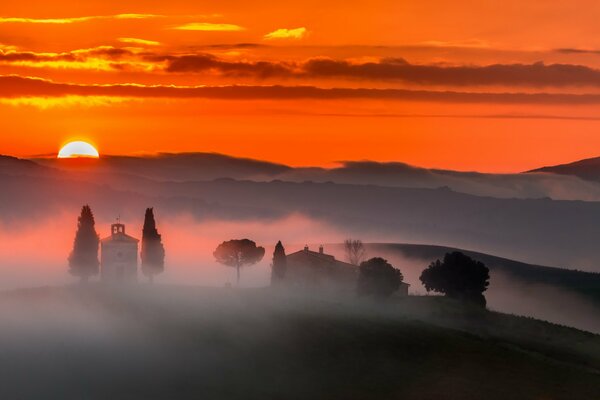 Die Schönheit des morgendlichen Sonnenuntergangs und die Stadt, die durch den Nebel durchscheint