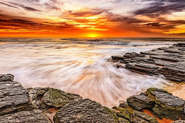 Felsiger Strand im Hintergrund des Sonnenuntergangs