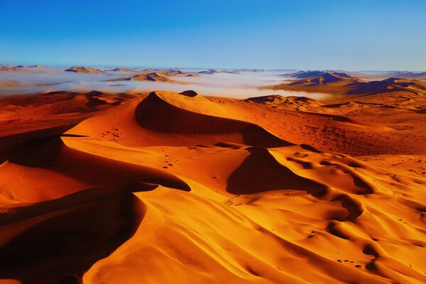 Leuchtend orangefarbene Dünen vor dem Hintergrund des blauen Himmels