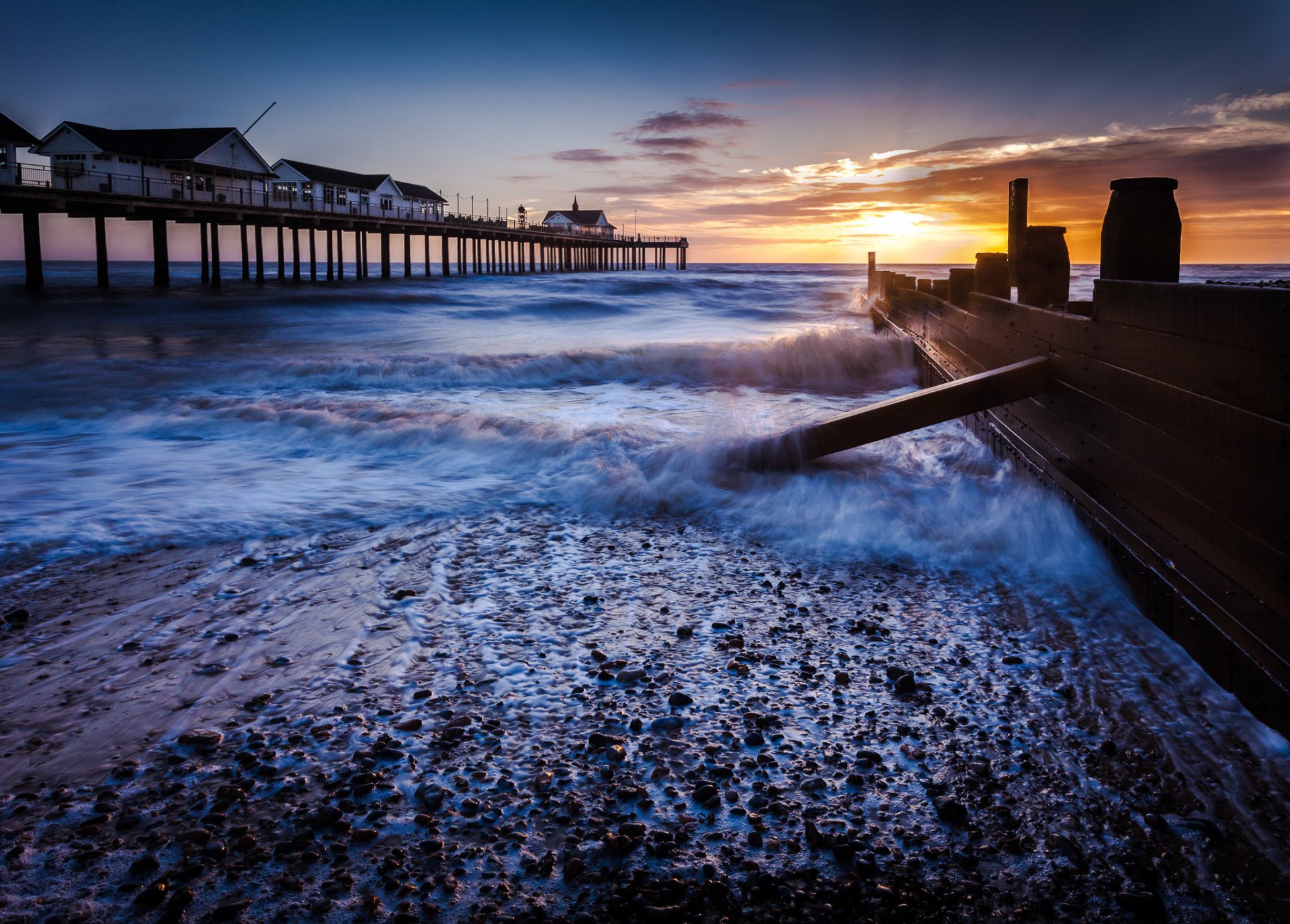 ea waves shore surf beach rocks morning sky sun sunrise clouds fence pier house