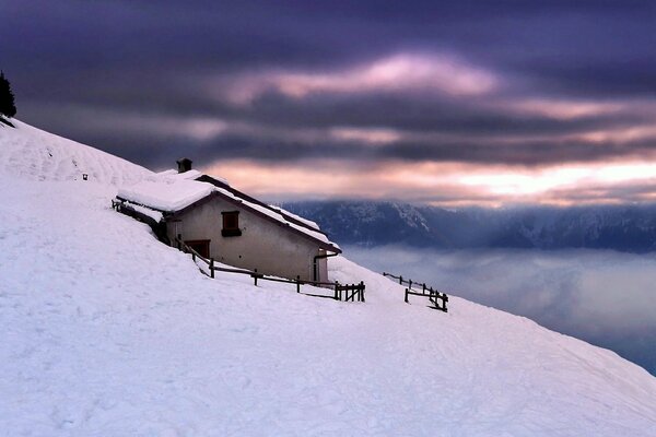 Capanna solitaria in un cumulo di neve sul fianco di una montagna