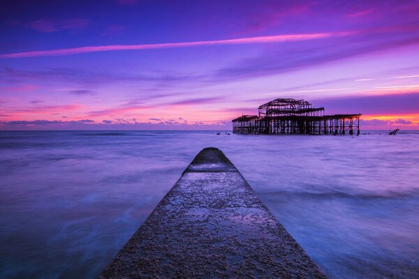 Pier going into the lilac sea at sunset