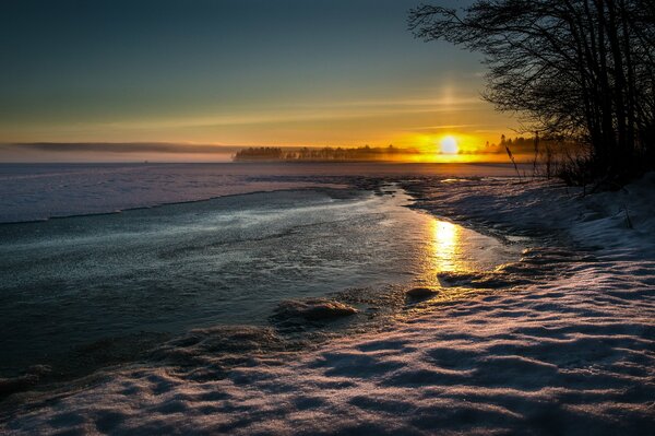 Abendlicher Winter Sonnenuntergang mit nach und nach frierendem Wasser