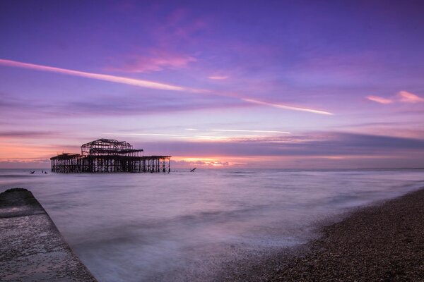 Purple sky. Pier by the sea. Evening landscape of Great Britain