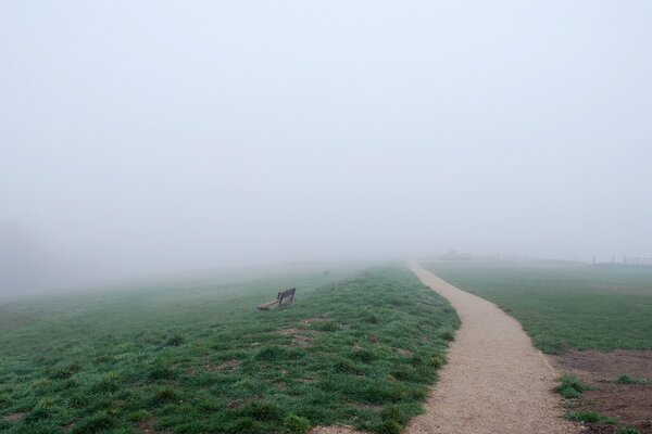 En el camino hacia el campo hay un banco y una niebla