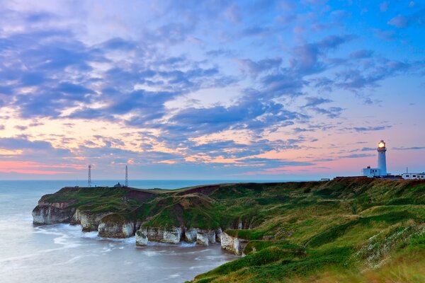 La orilla del mar con un faro al amanecer