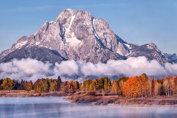 See vor dem Hintergrund der Berge und herbstlichen Wald