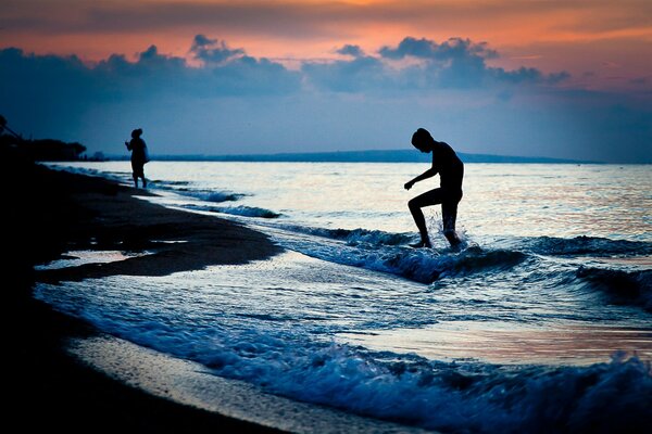 Persone in riva al mare sullo sfondo del tramonto