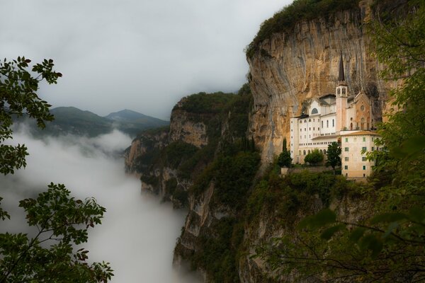 Ein Schloss in einem Berg. Dichter Nebel breitet sich am unteren Rand des Berges aus