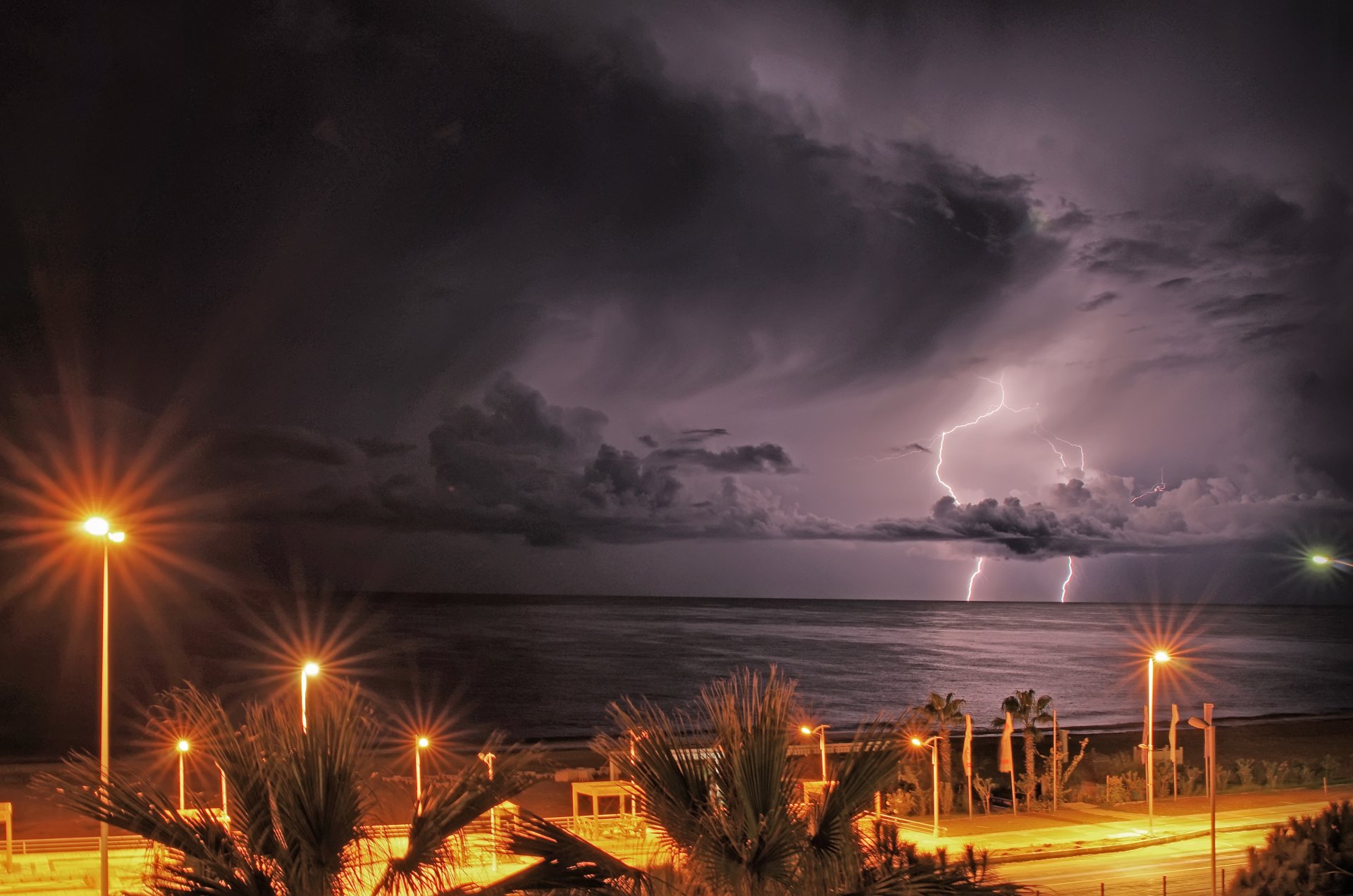 meer küste uferpromenade abend lampen lichter himmel wolken blitze