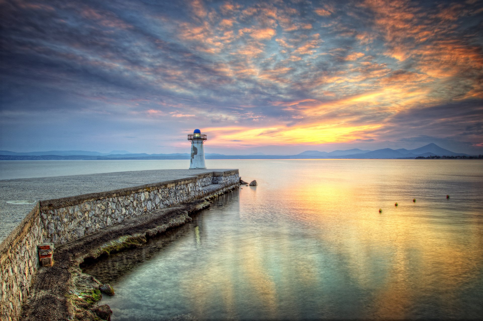 montañas bahía muelle faro puesta de sol