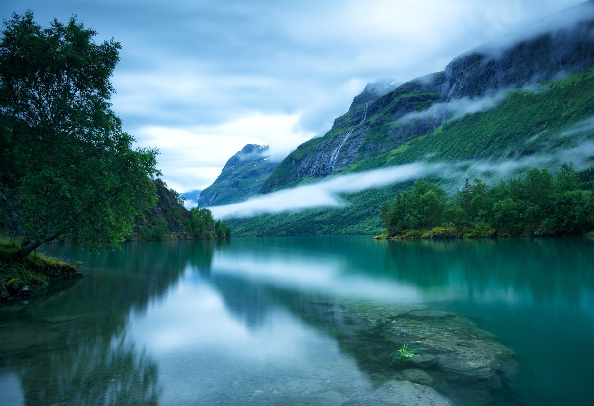 westnorwegen loenvatnet loen see glatte oberfläche boden steine skandinavische berge bäume nebel himmel wolken