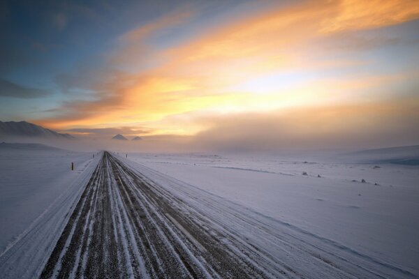 Strada invernale verso il nulla con un bel cielo al tramonto