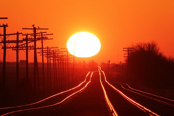 Die Schienen der Eisenbahn, die in den Sonnenuntergang gehen