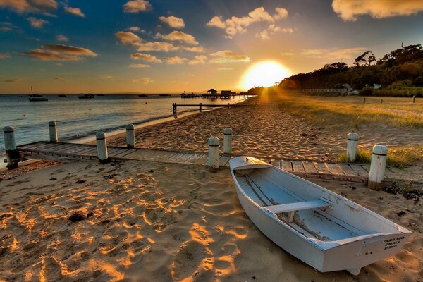 Coucher de soleil illumine le bateau sur la plage de sable