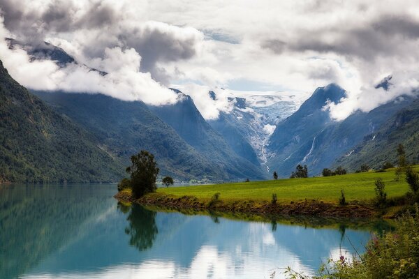 Wolken in den Bergen über einer grünen Wiese in Norwegen