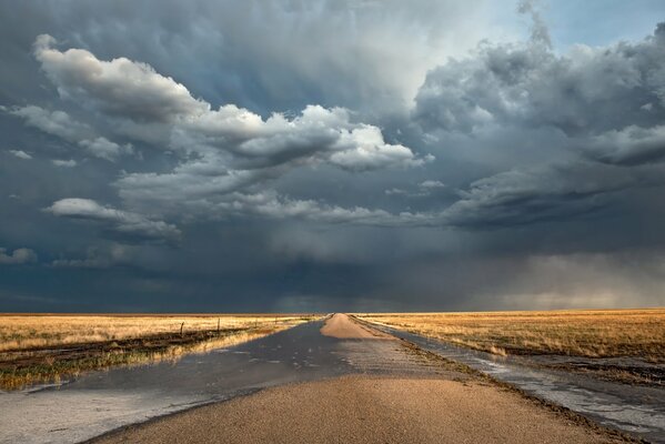 A road with an endless field and cloudy weather