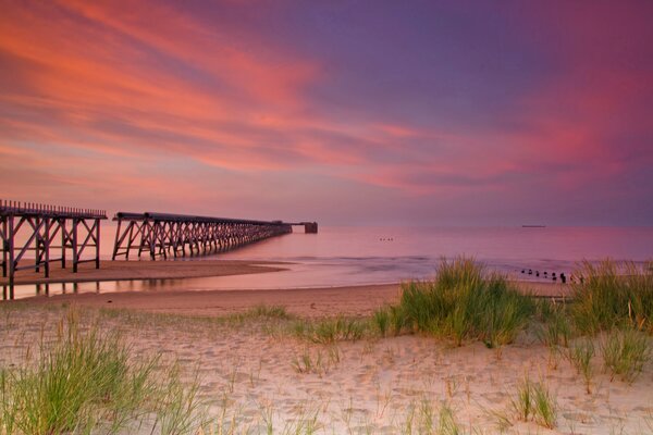 Sunset on the sea with sand and pier