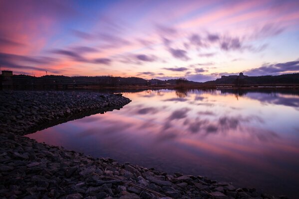 Reflection of clouds in the water among the rocky shore