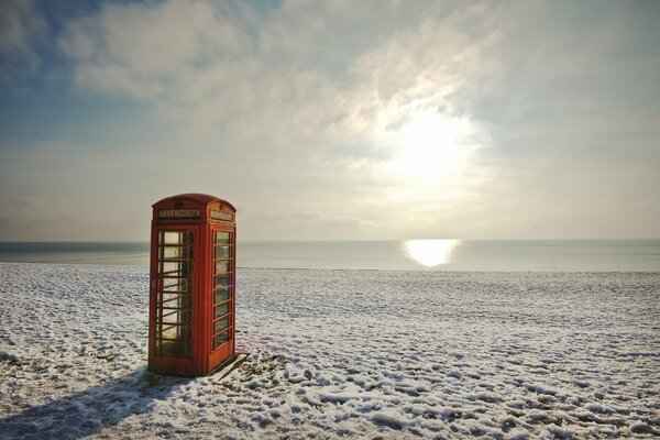 Cabina telefónica en la playa en invierno detrás del atardecer