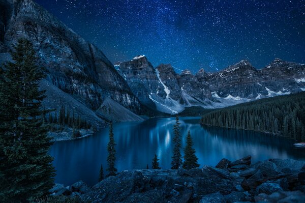 Lago en las montañas bajo el cielo estrellado nocturno