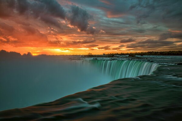 Hoher Wasserfall in den Strahlen der aufgehenden Sonne