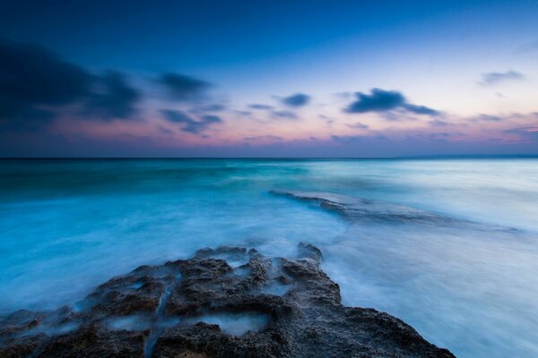 Seascape. Stone coast and blue clouds