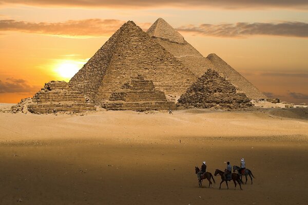 Bild einer leuchtend gelben Pyramide vor dem Hintergrund des Sonnenuntergangs, Reiter in der Wüste