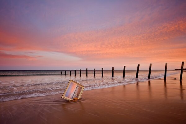 Pintura en la arena junto al mar contra el cielo rosa