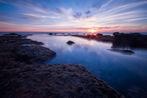 A beach with rocks on the horizon by the sea