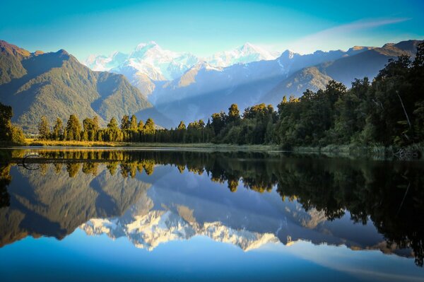 Berge und Wald spiegeln sich auf der blauen Wasseroberfläche wider